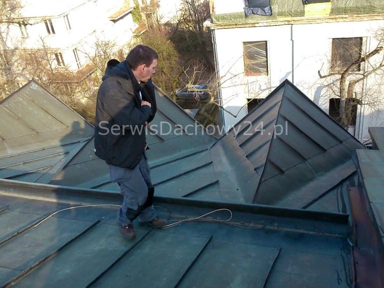 Dekarz sprawdza przeciekający dach z blachy